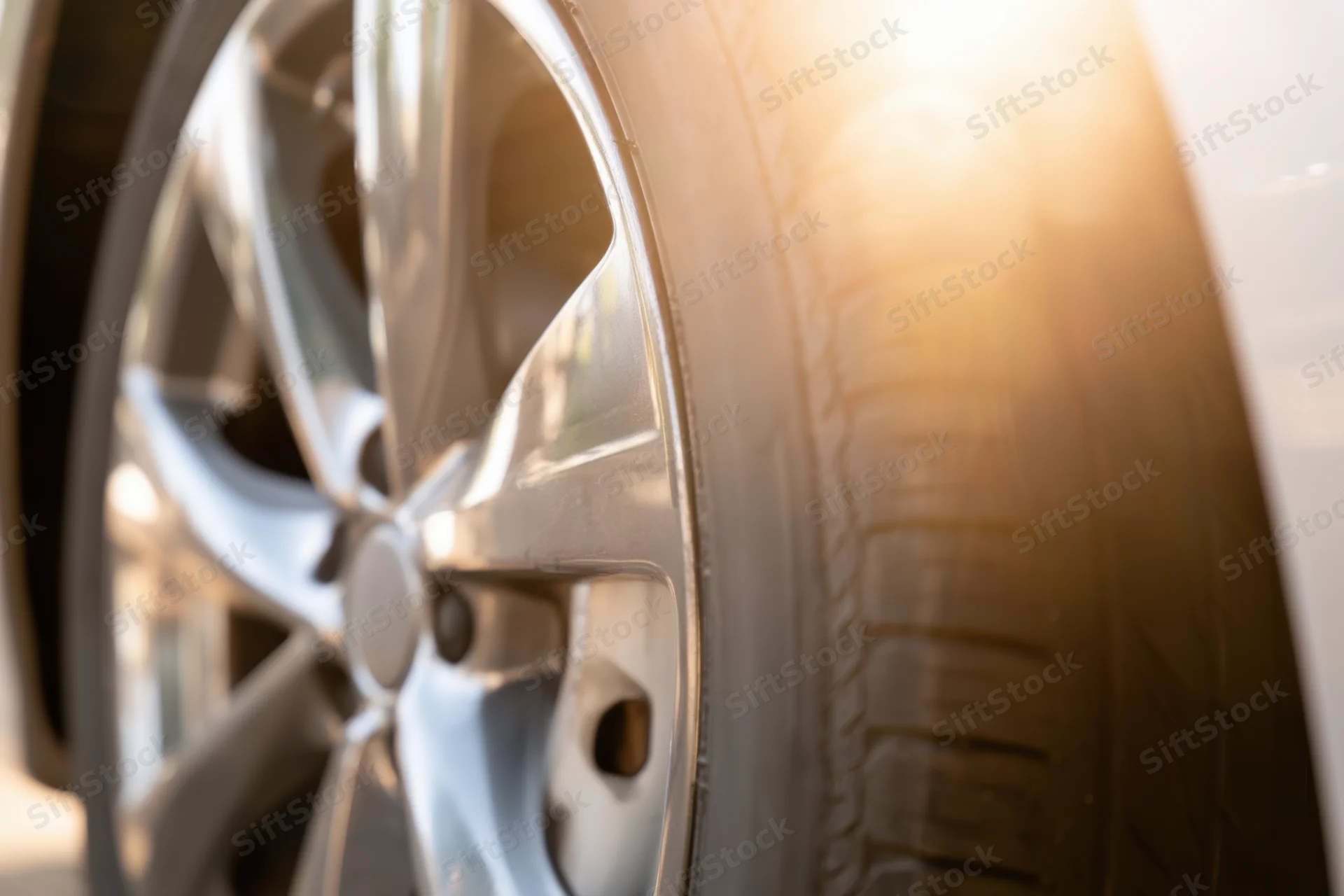 Close-up of a car wheel with a sleek alloy rim and tire under warm sunlight