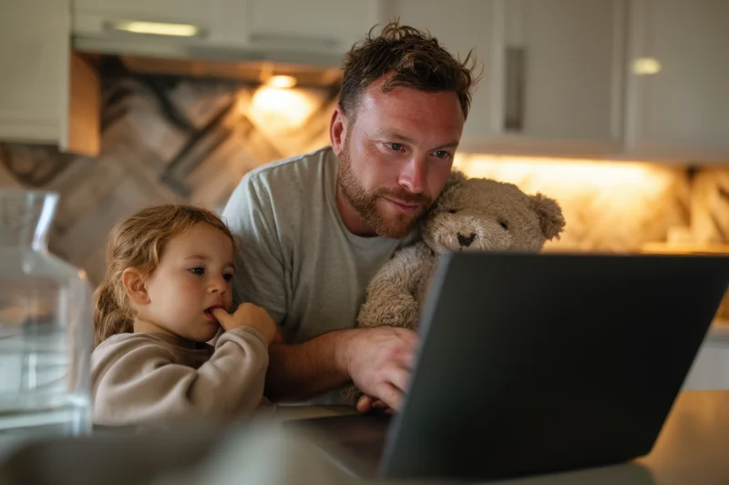 Father and daughter using laptop together in kitchen