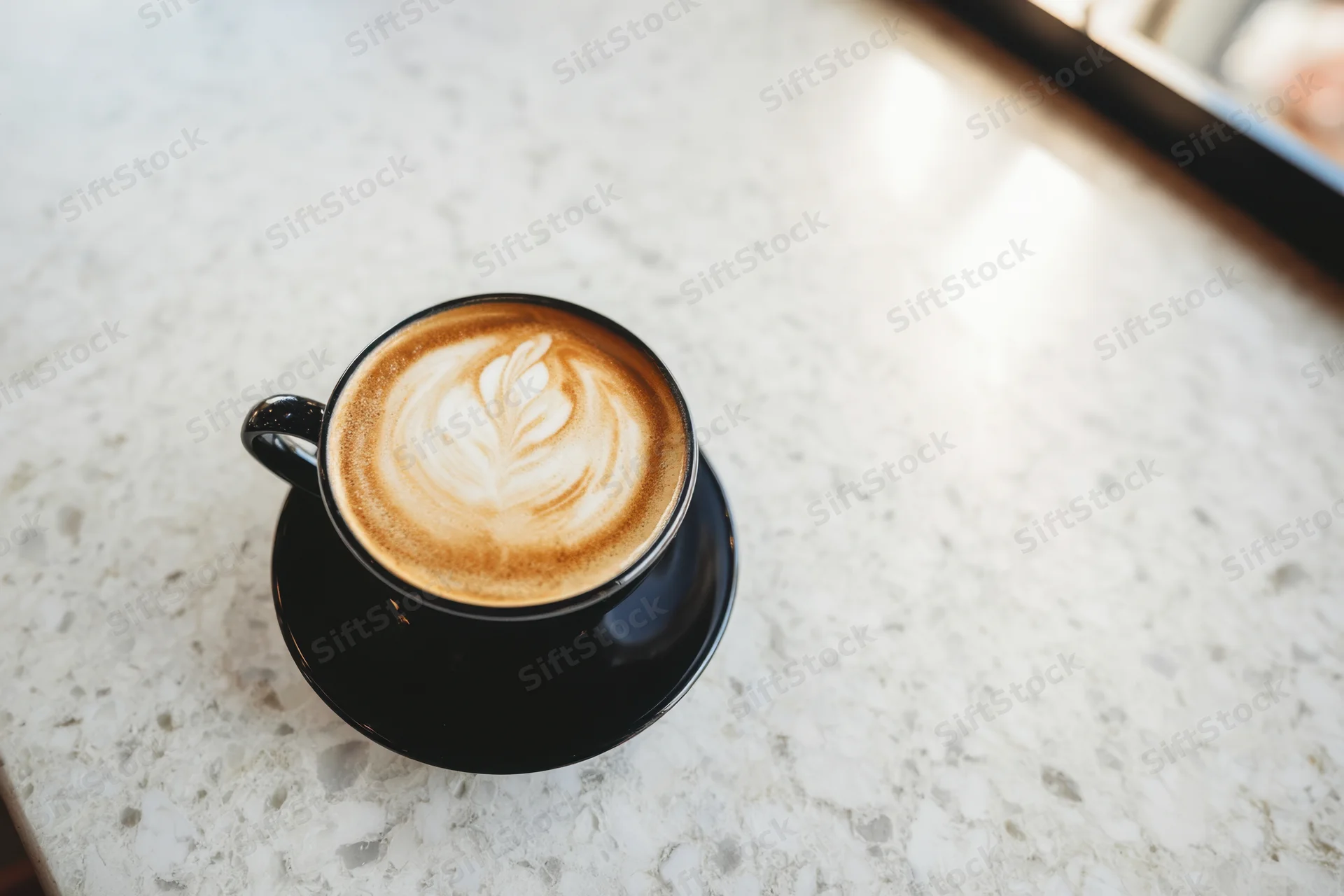 Black cup of coffee with latte art on a marble countertop