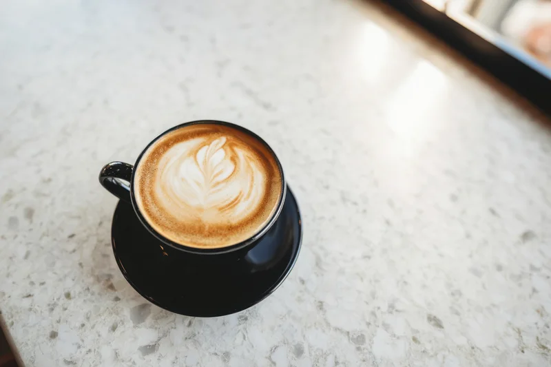 Black cup of coffee with latte art on a marble countertop
