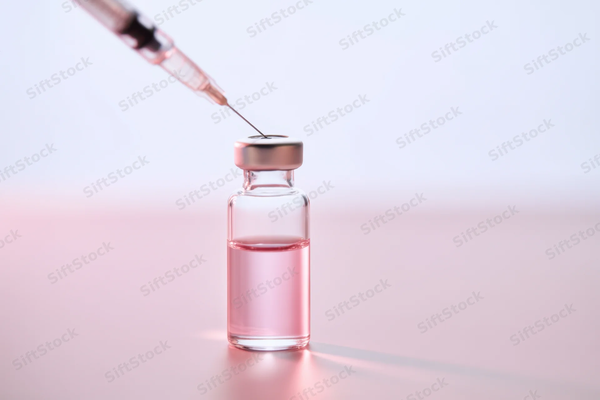 Syringe drawing liquid from a glass vial on a smooth surface