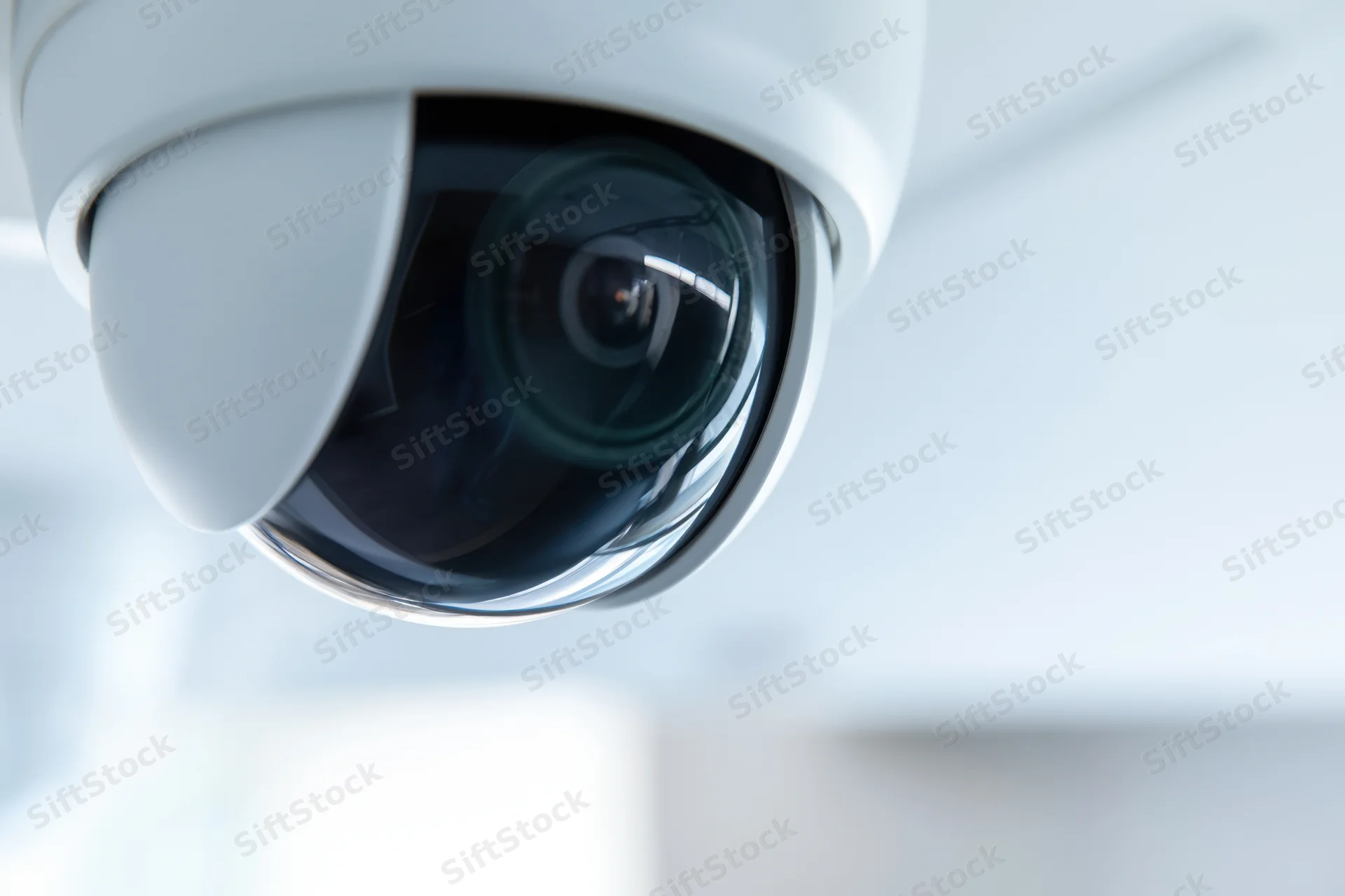 Close-up of a white dome security camera mounted on a ceiling indoors
