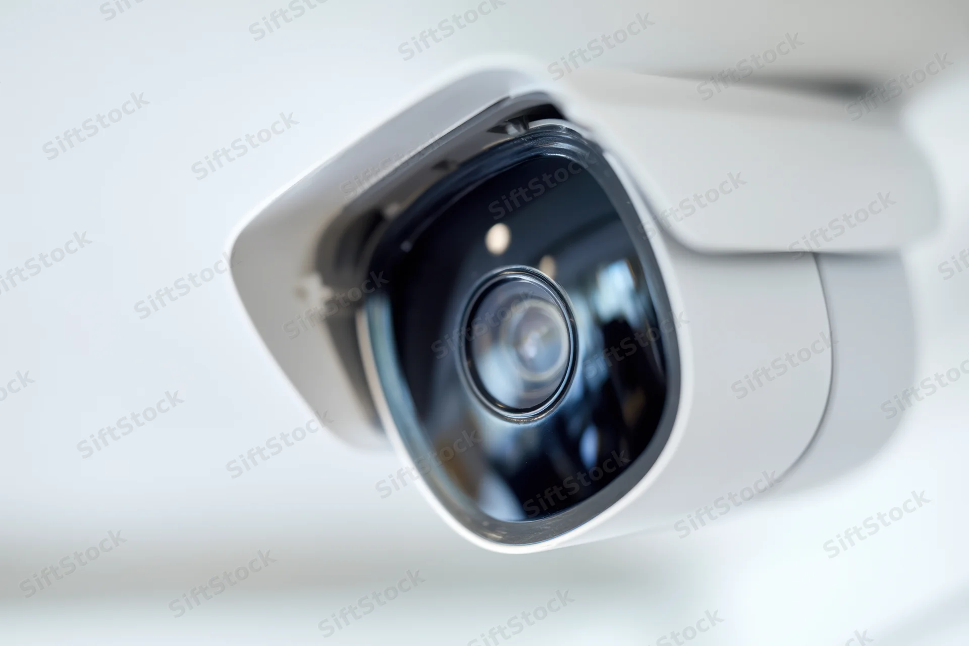 Close-up of a white security camera mounted on a ceiling, showing its lens and housing in focus