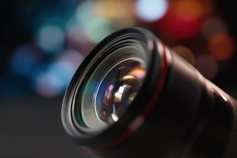 Closeup of a professional camera lens with intricate glass structure against a blurred bokeh background