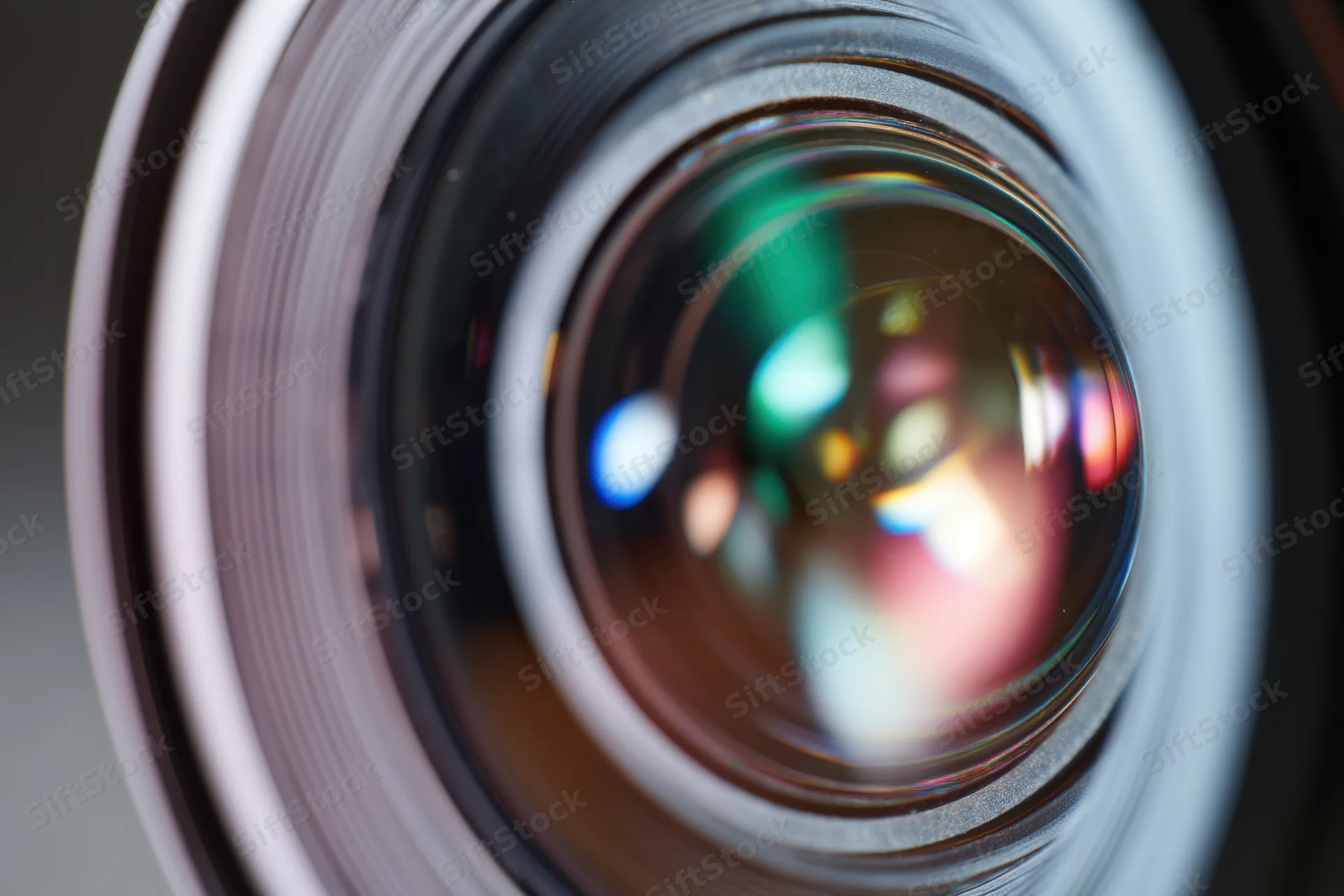 Closeup of a professional camera lens showing intricate glass elements and colorful reflections in the aperture