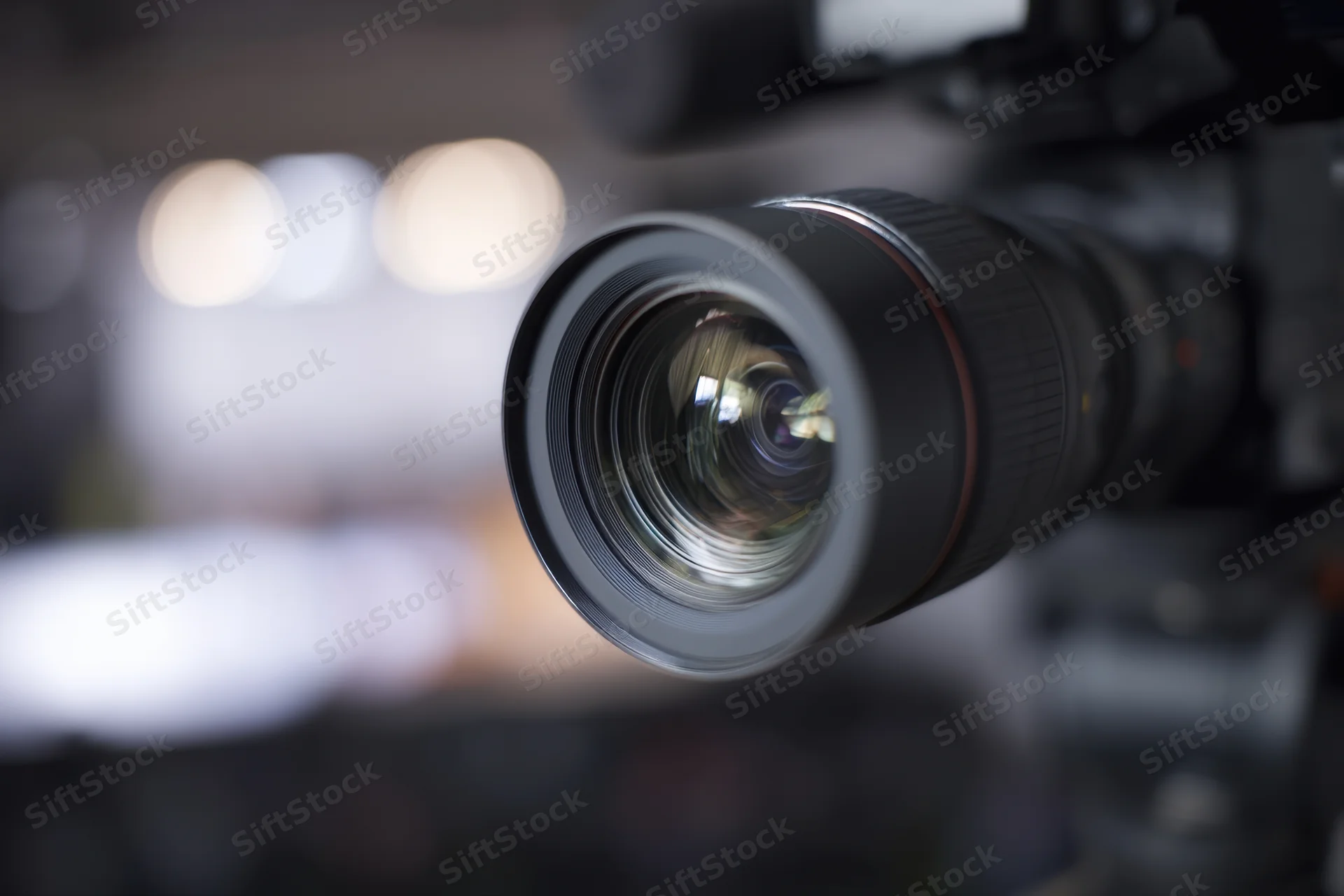 Professional video camera lens in closeup focus with blurred studio background