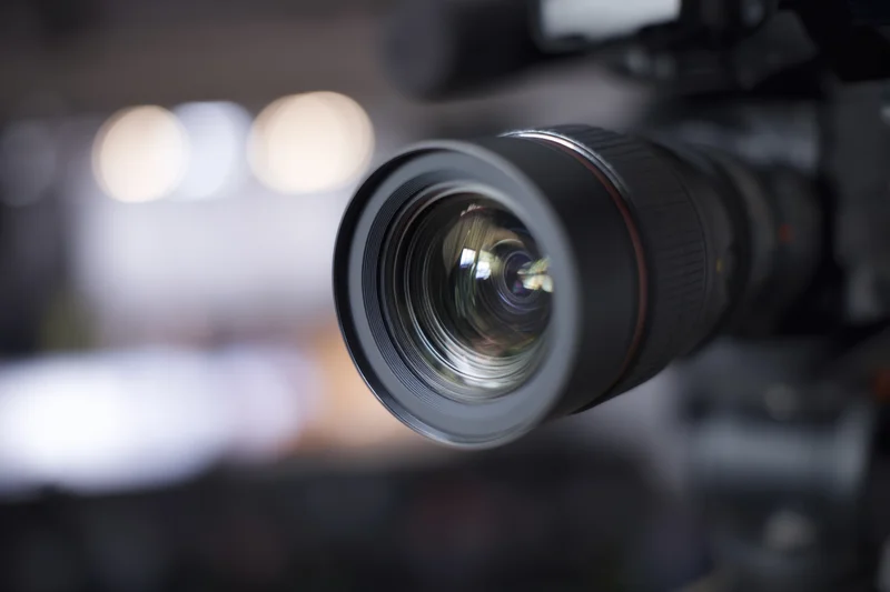 Professional video camera lens in closeup focus with blurred studio background