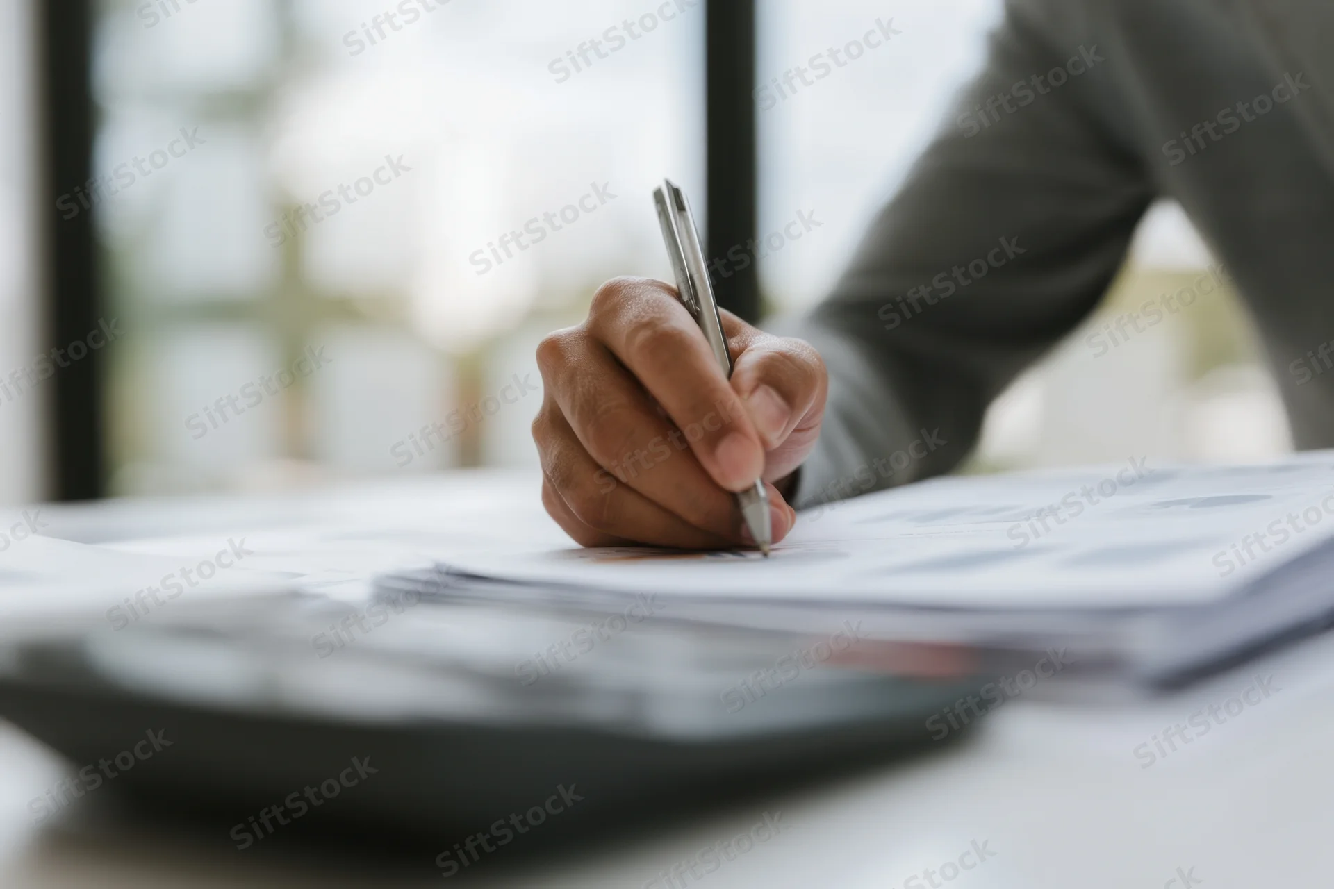 Hand writing on document with pen at office desk
