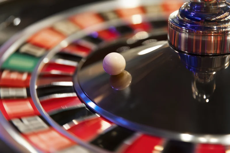 Spinning roulette wheel with white ball and metallic spinner in casino setting
