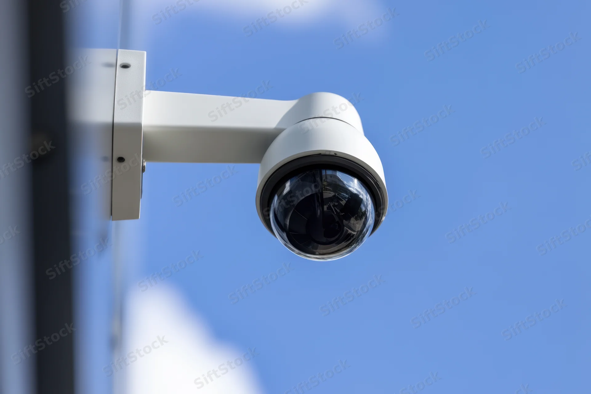 Security camera mounted on building exterior under clear blue sky