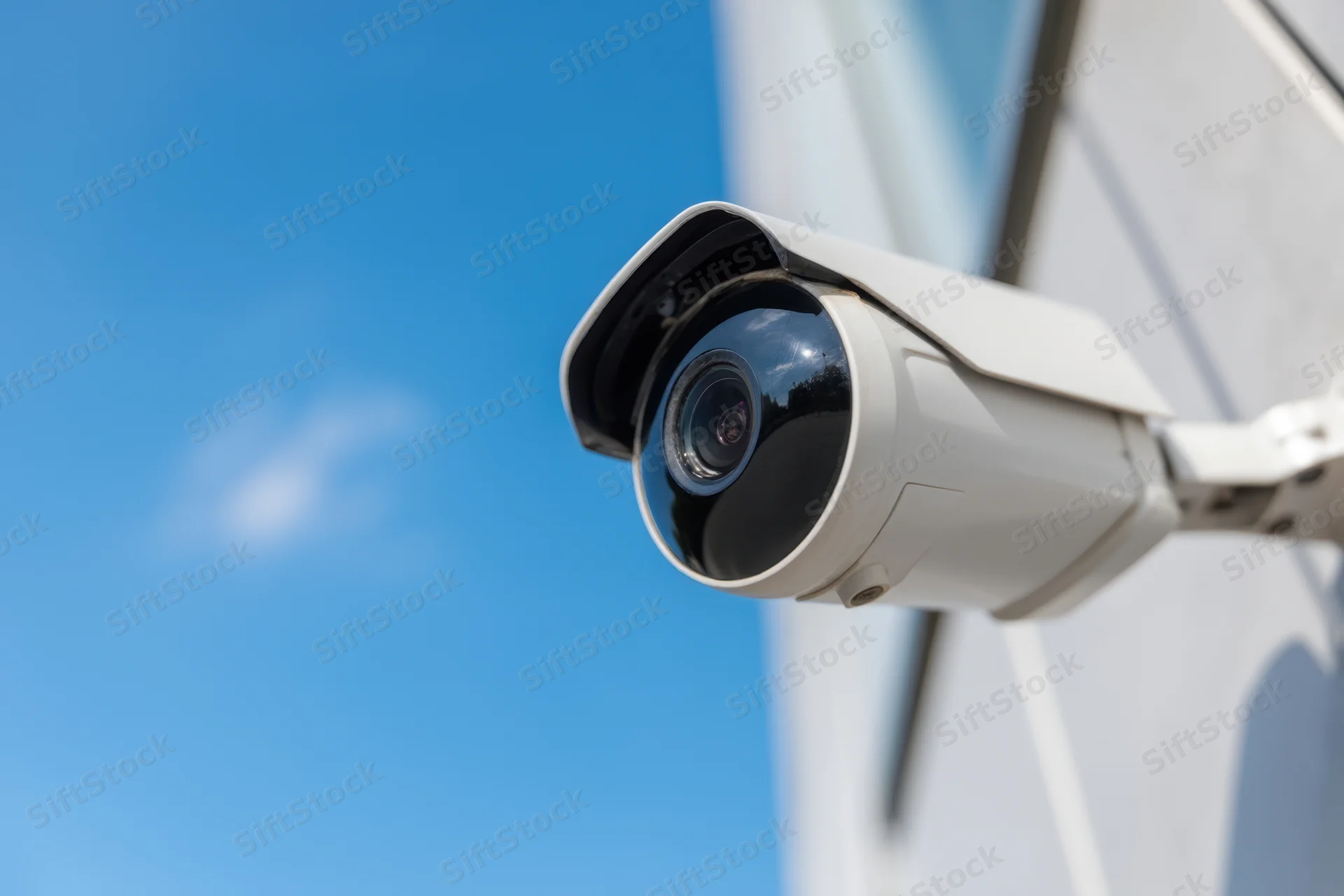Security camera mounted on a building exterior under a clear blue sky