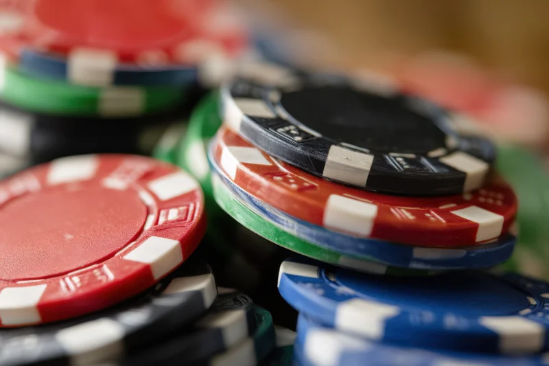 Stacked poker chips in red green blue black and white arranged in piles with shallow focus and blurred background