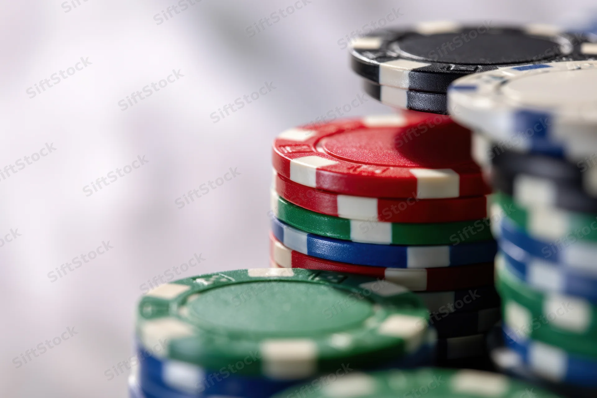 Stacks of poker chips in red, green, blue, and black arranged closely with blurred background