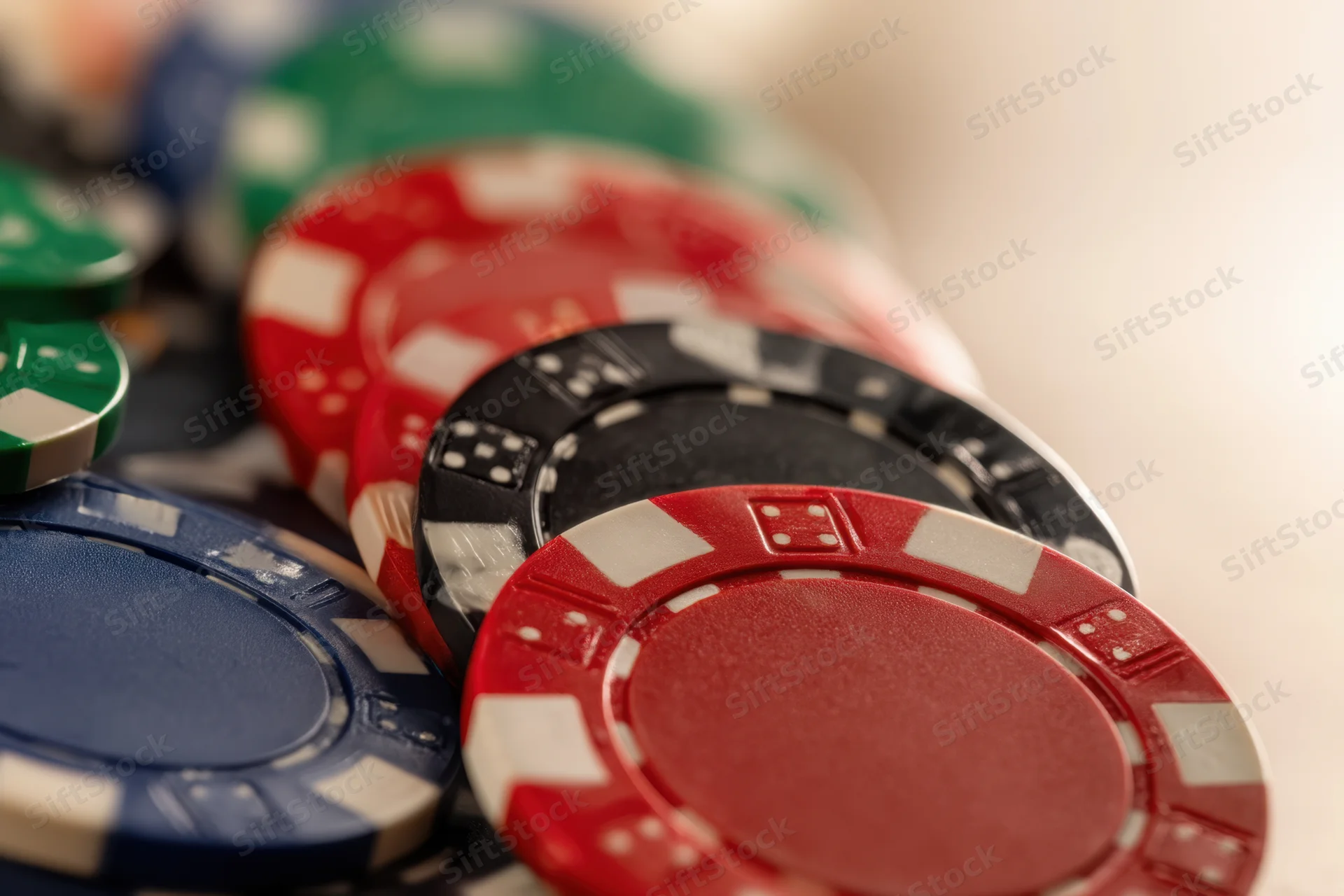 Poker chips stacked in various colors with shallow depth of field focus on red and black chips