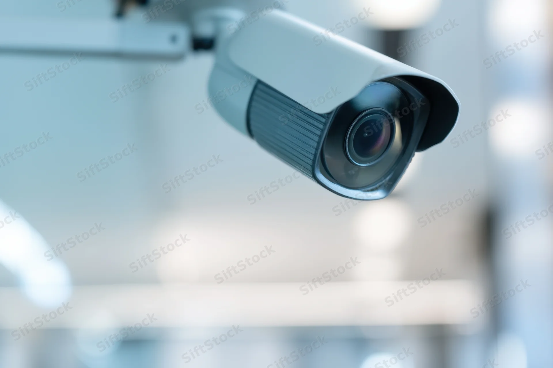 Surveillance camera mounted on wall in indoor setting with blurred background