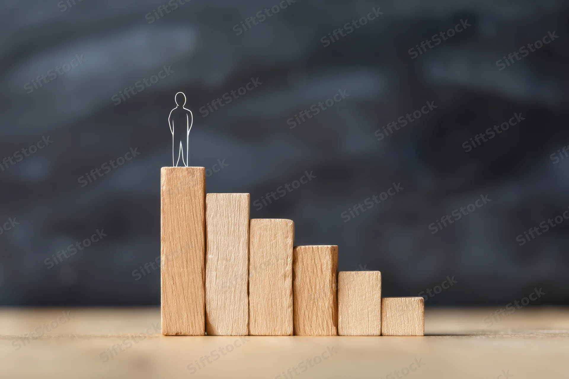 Wireframe figure standing atop wooden blocks arranged in ascending staircase on wooden surface