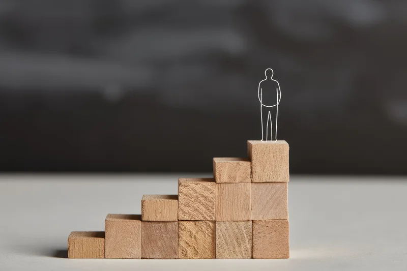 Wireframe person standing atop wooden block staircase on light surface