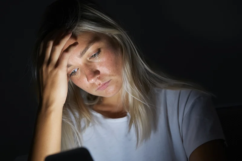 Of a young woman in a dark room illuminated by the screen