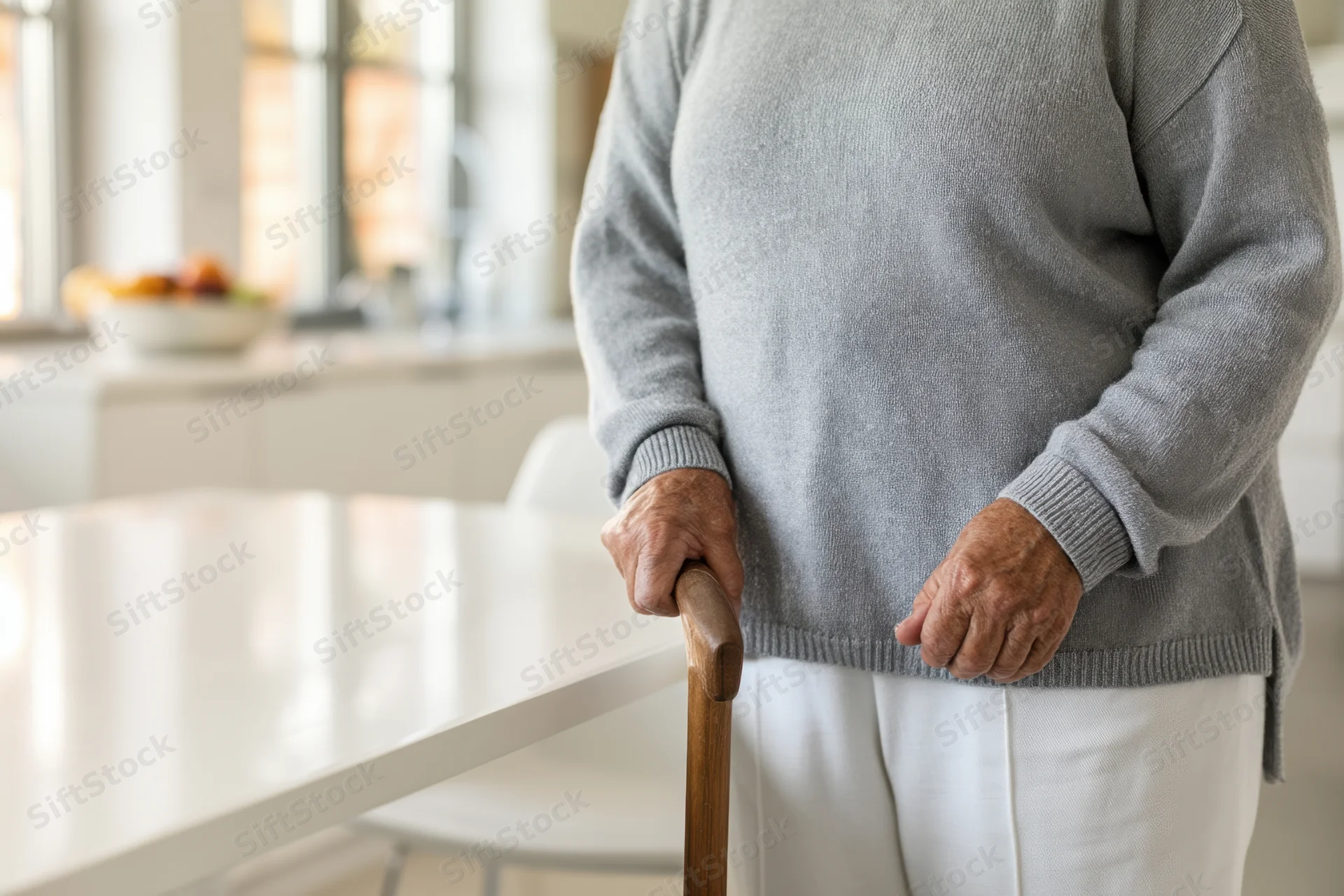 Senior woman standing with wooden cane in modern kitchen interior