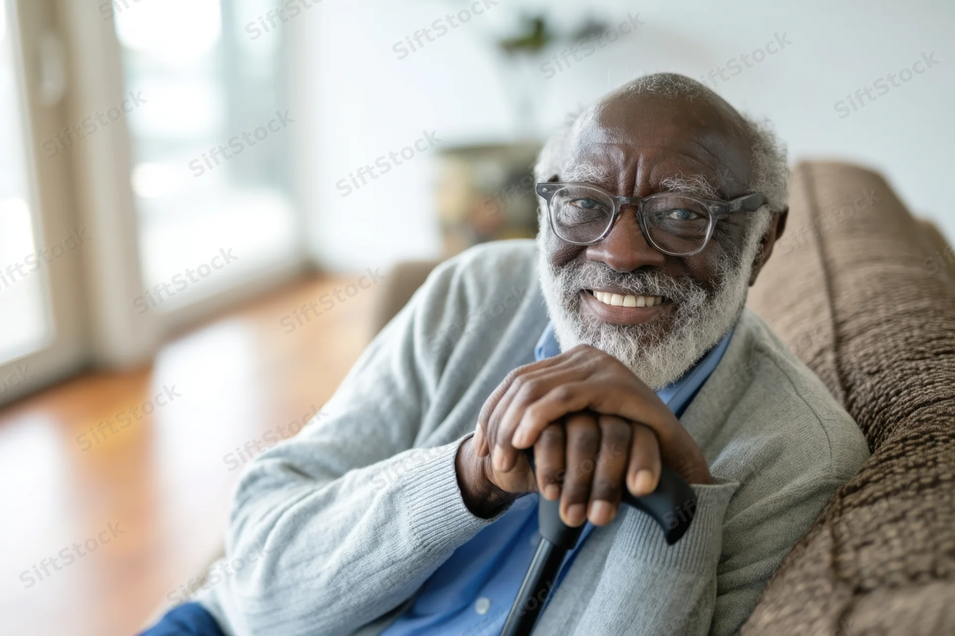 Senior man smiling while sitting on couch holding cane in living room