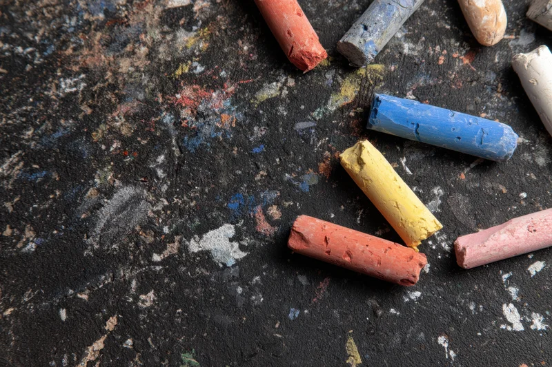 Colorful chalk sticks scattered on a textured black surface