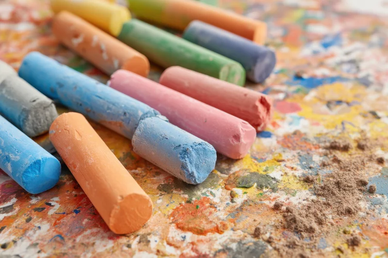 Colorful art pastels arranged on a textured surface covered in pigment residue