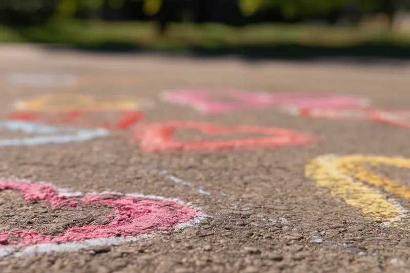 Colorful heart shapes drawn with chalk on textured asphalt pavement outdoors