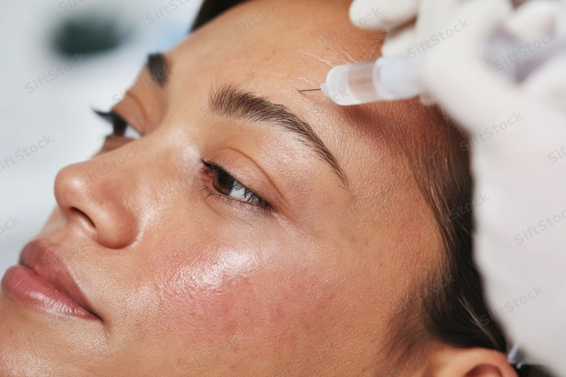 Woman receiving botox injection on forehead in medical clinic