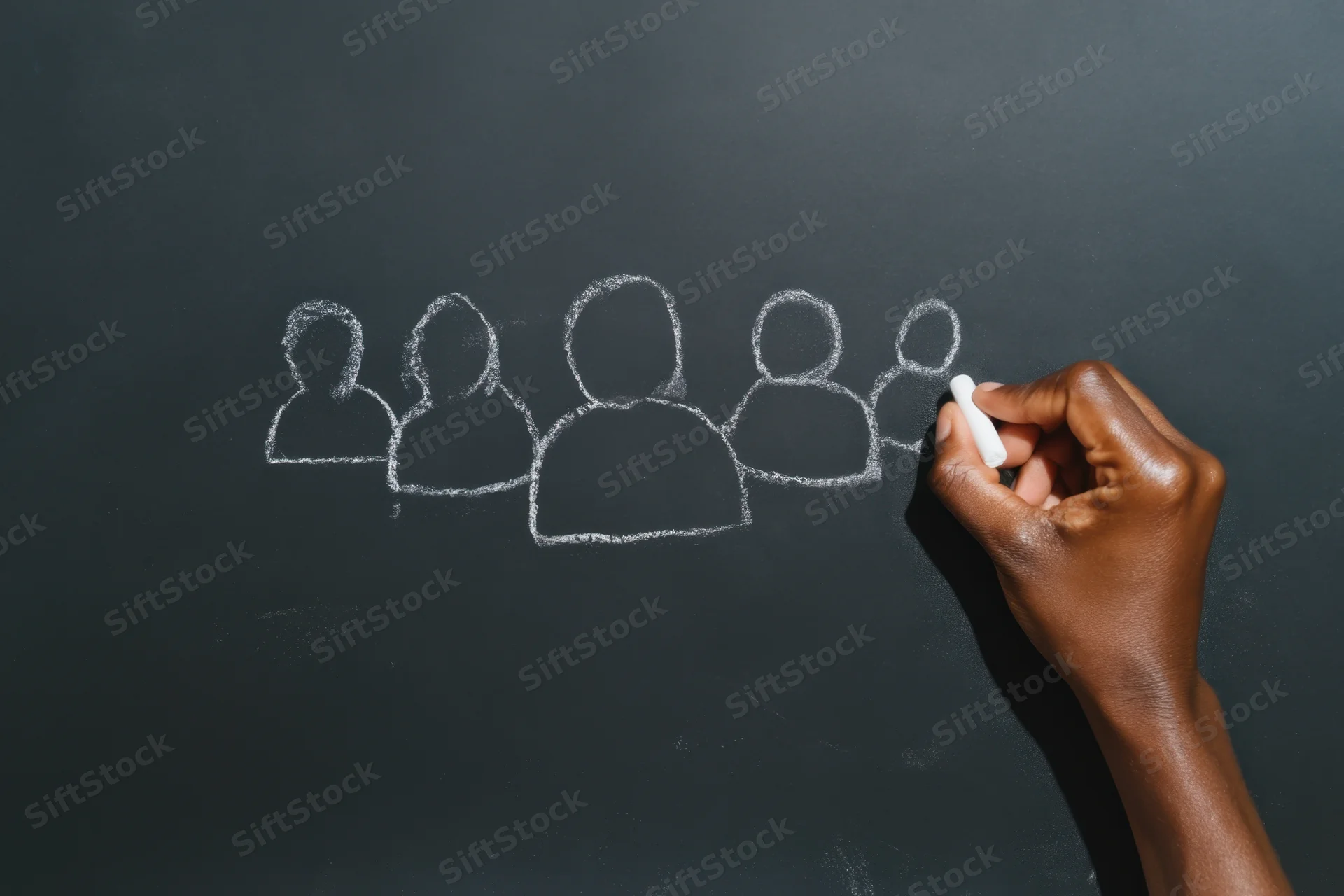 Hand drawing human silhouettes with chalk on a blackboard