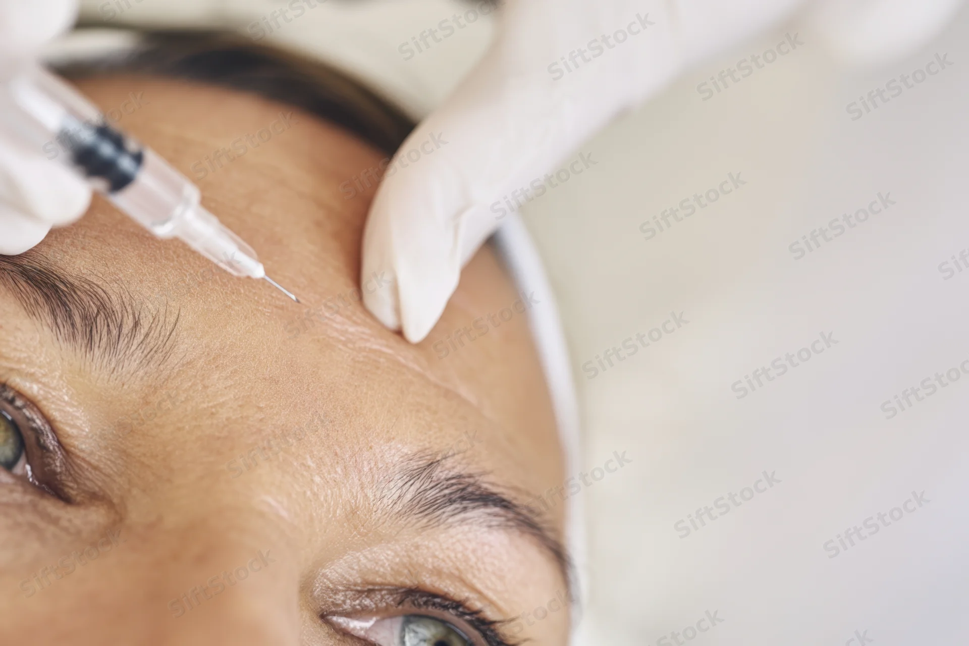 Woman receiving facial injection on forehead in cosmetic clinic