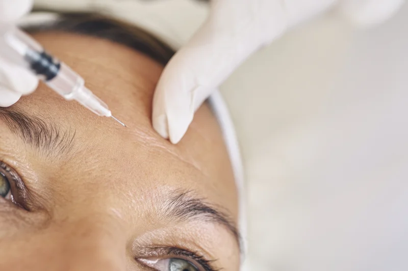 Woman receiving facial injection on forehead in cosmetic clinic