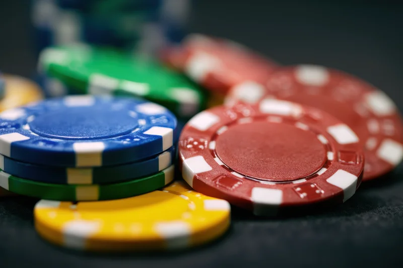 Poker chips stacked and scattered on a dark surface with shallow depth of field