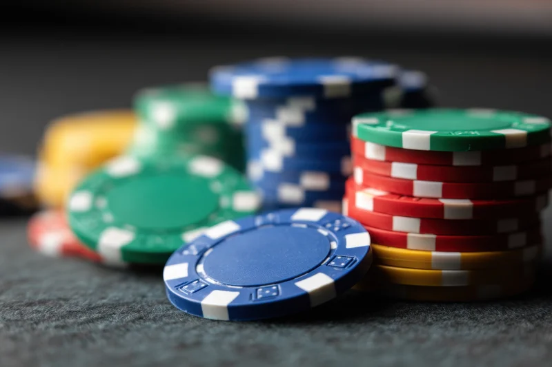 Stacks of colorful poker chips arranged on a dark textured surface with shallow depth of field