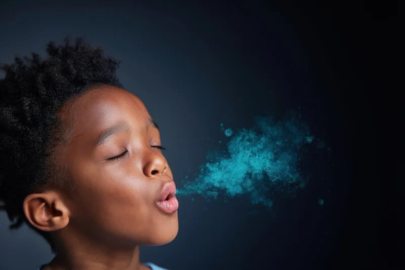 Child exhaling stylized blue virus particles against dark background