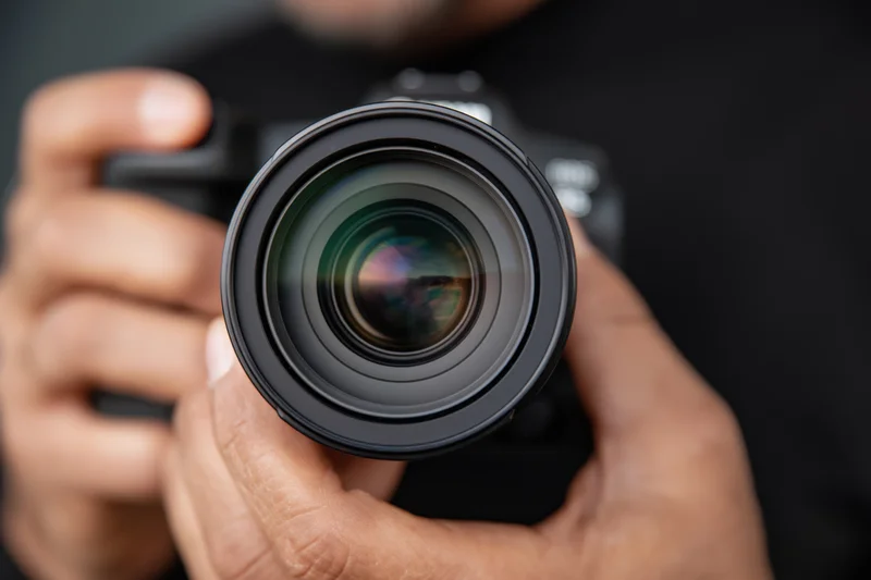 Close-up of hands holding a professional DSLR camera with lens in focus