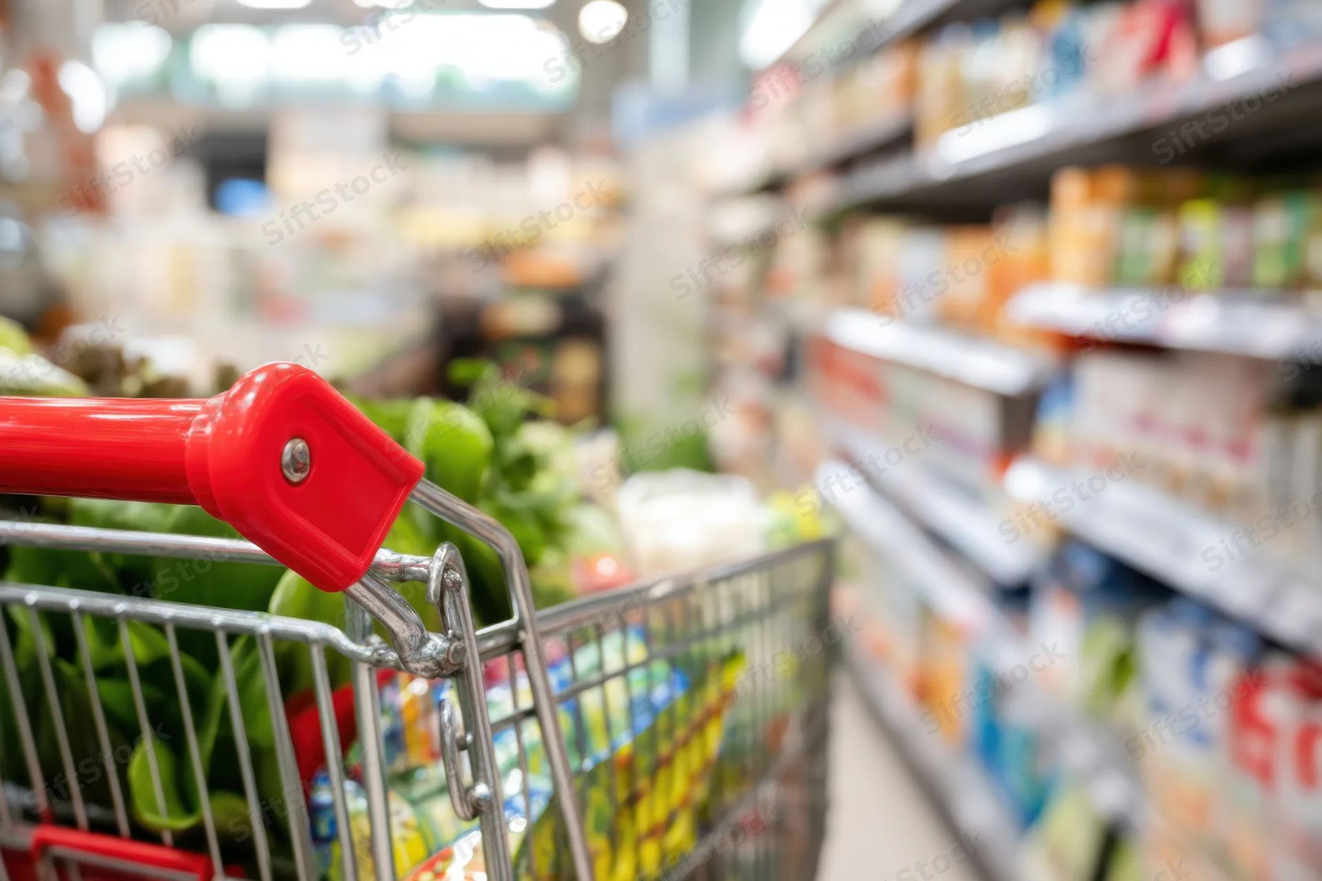Metal shopping cart with vegetables in a supermarket aisle