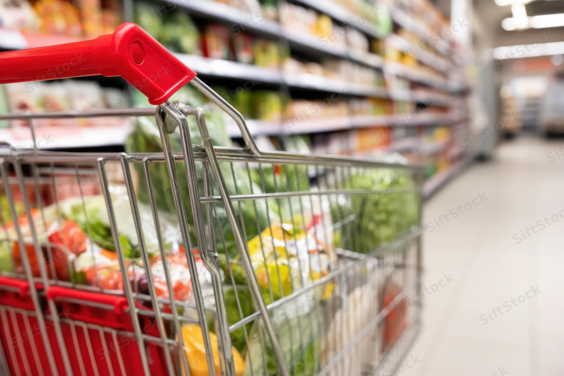 Metal shopping cart filled with produce in a supermarket aisle