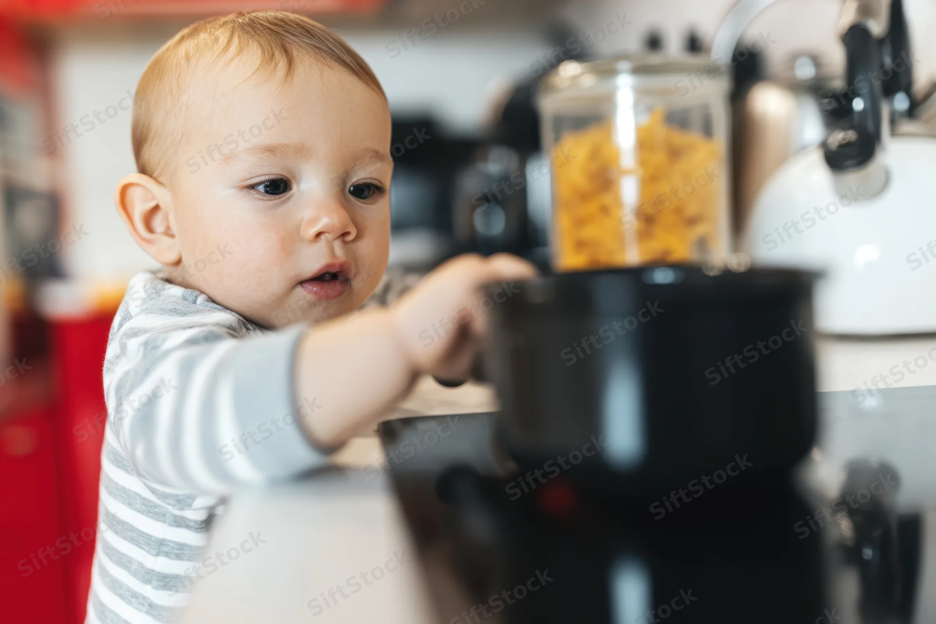 Curious baby reaching for a pot on a kitchen countertop