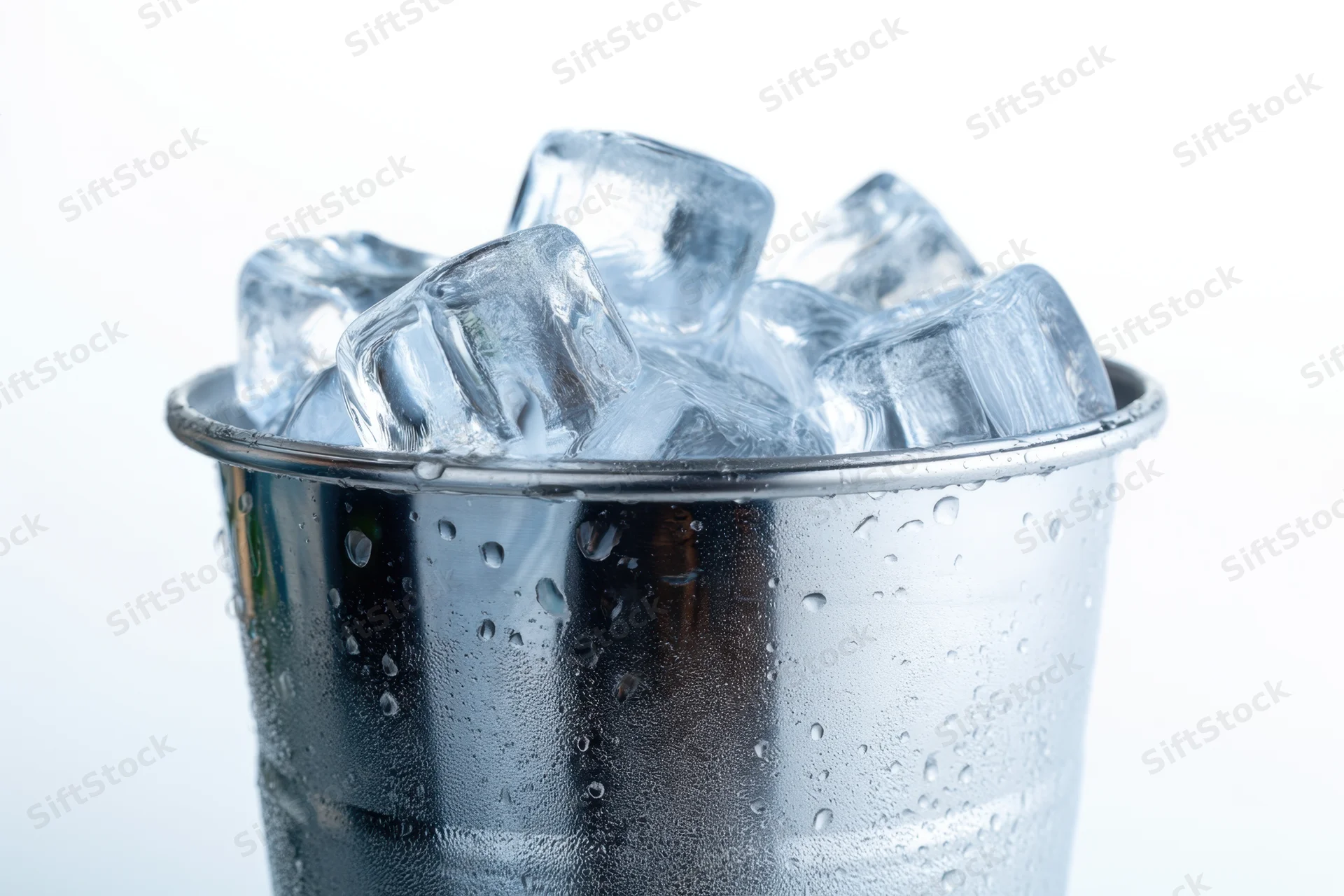 Metallic bucket filled with clear ice cubes showing condensation on the surface