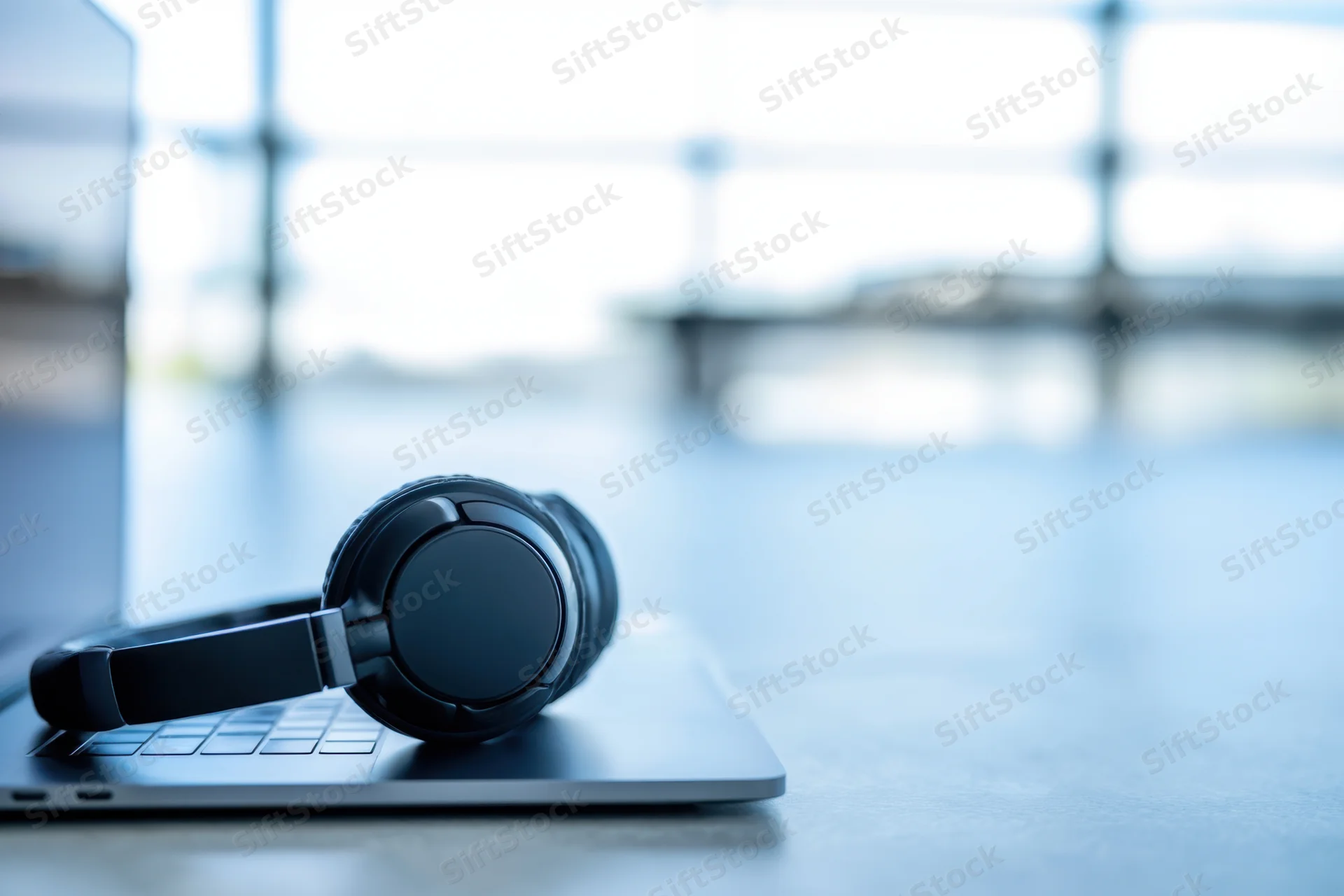 Black overear headset resting on closed laptop on office desk