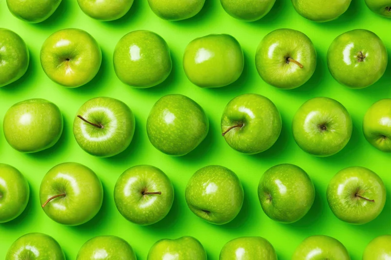 Green apples arranged in a seamless repeating grid pattern on a bright green background