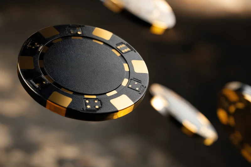 Black and gold poker chips in motion over a glossy reflective surface