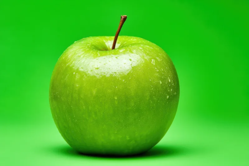 Shiny green apple with water droplets on a green background