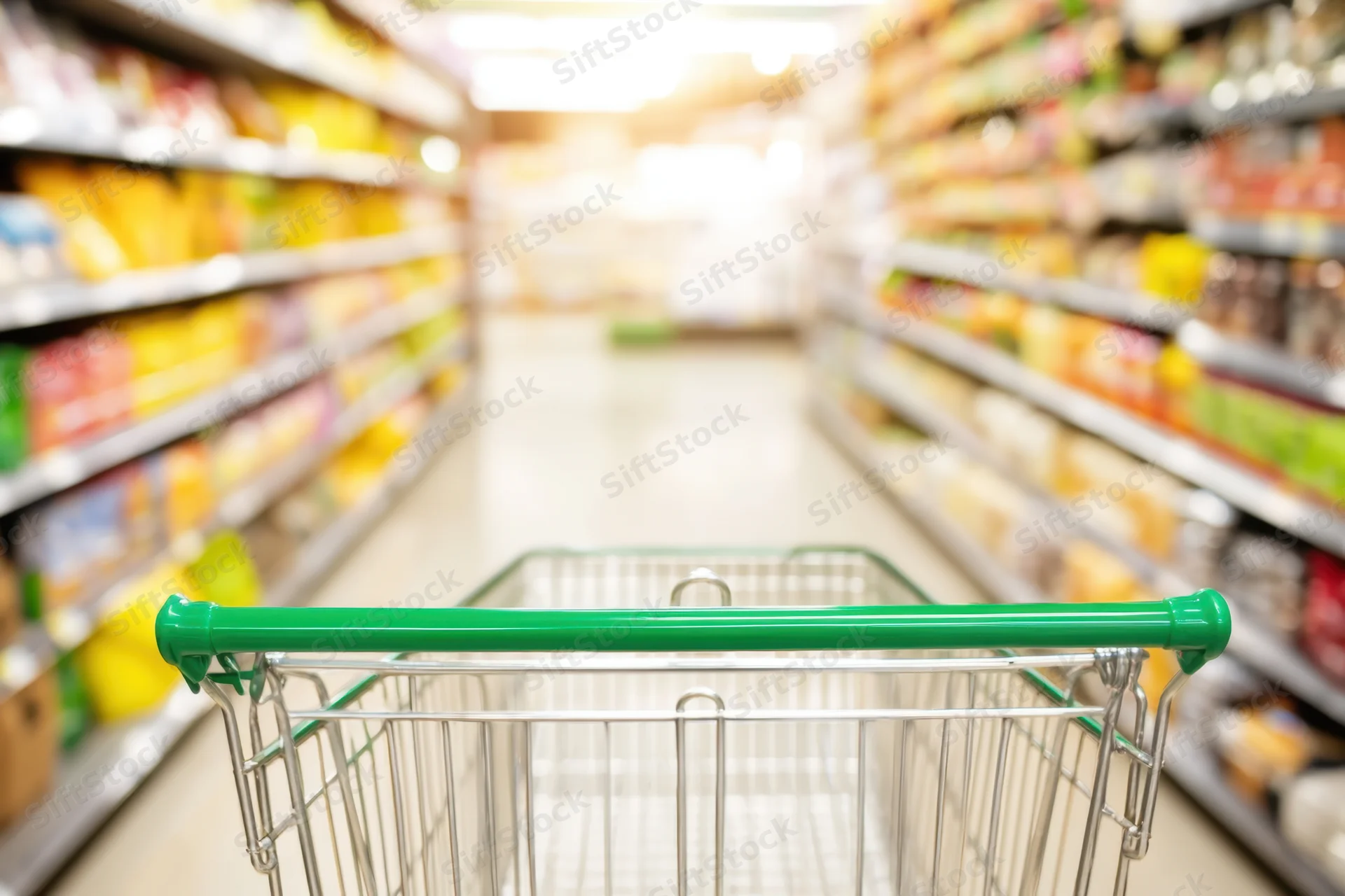 Shopping cart in foreground facing down a supermarket aisle with shelves of products on both sides