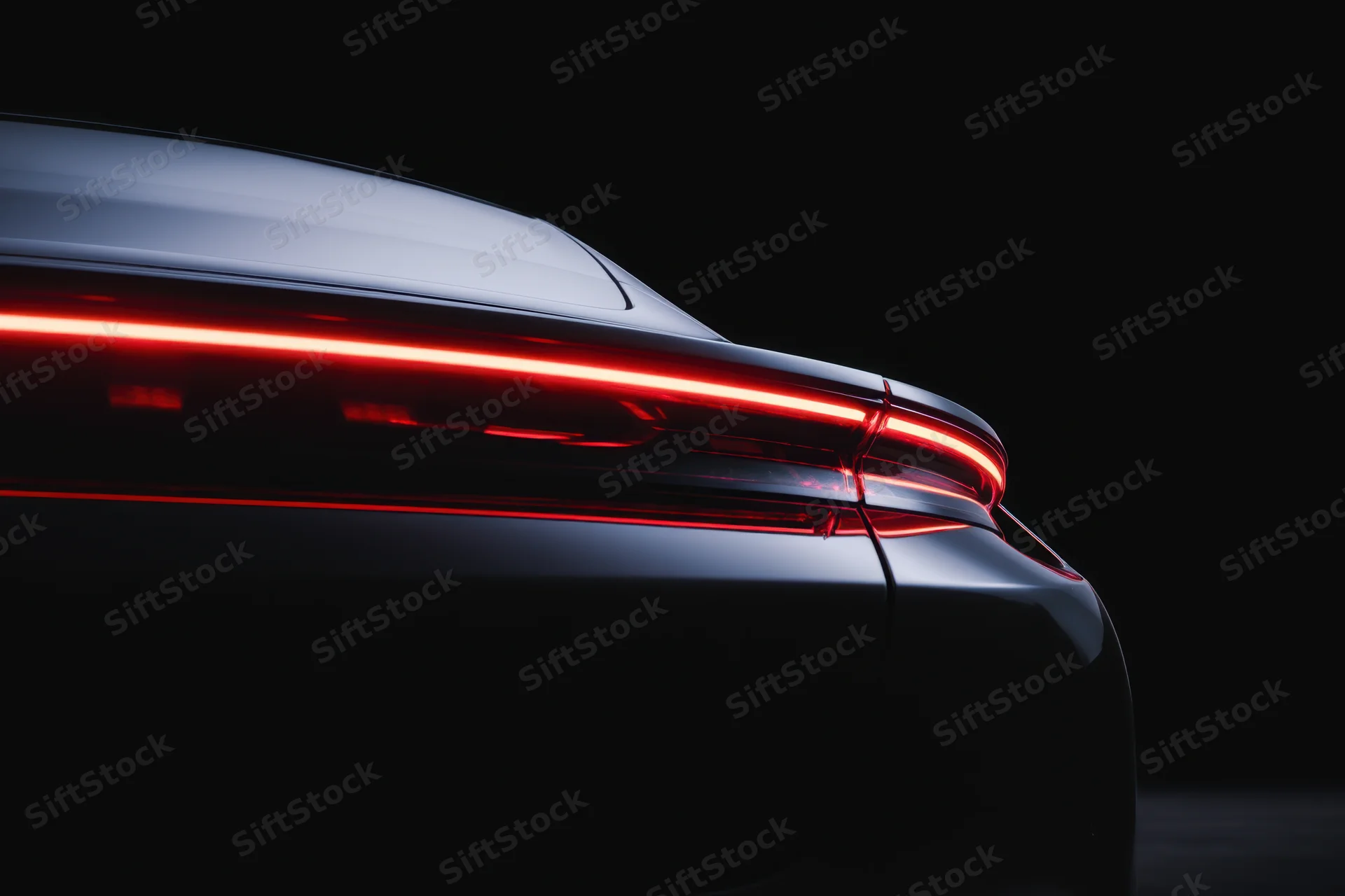 Rear view of a sleek modern electric car with glowing red taillights in dark studio setting