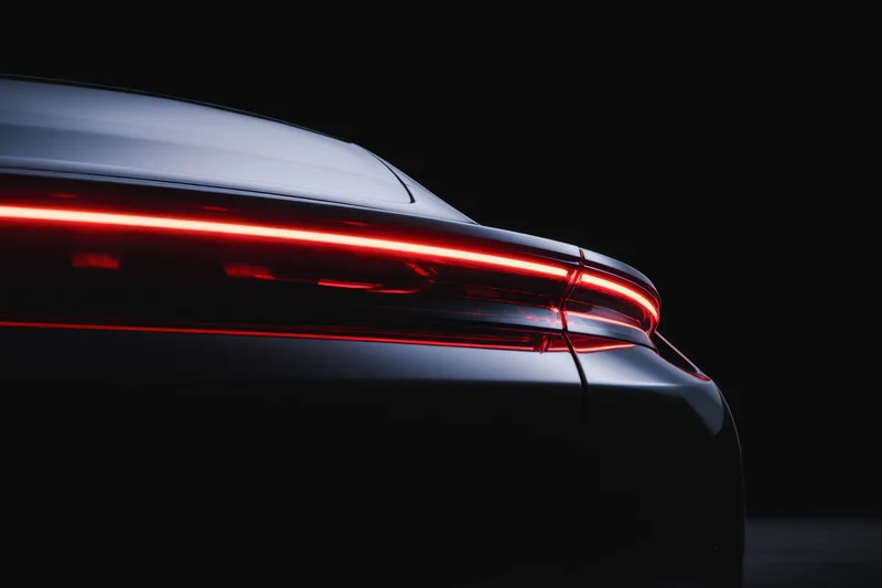 Rear view of a sleek modern electric car with glowing red taillights in dark studio setting