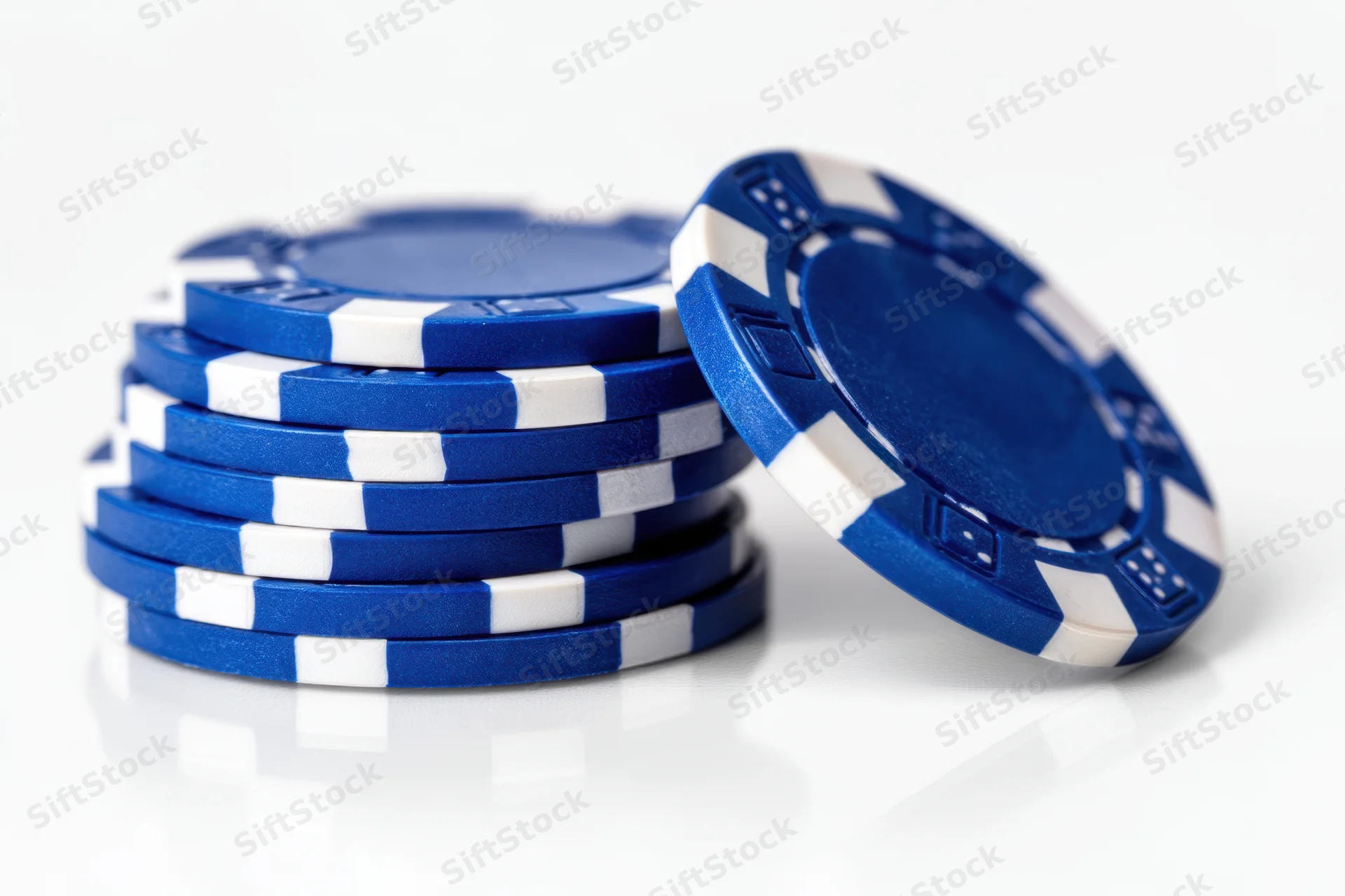 Stack of blue poker chips with white stripes on reflective white surface