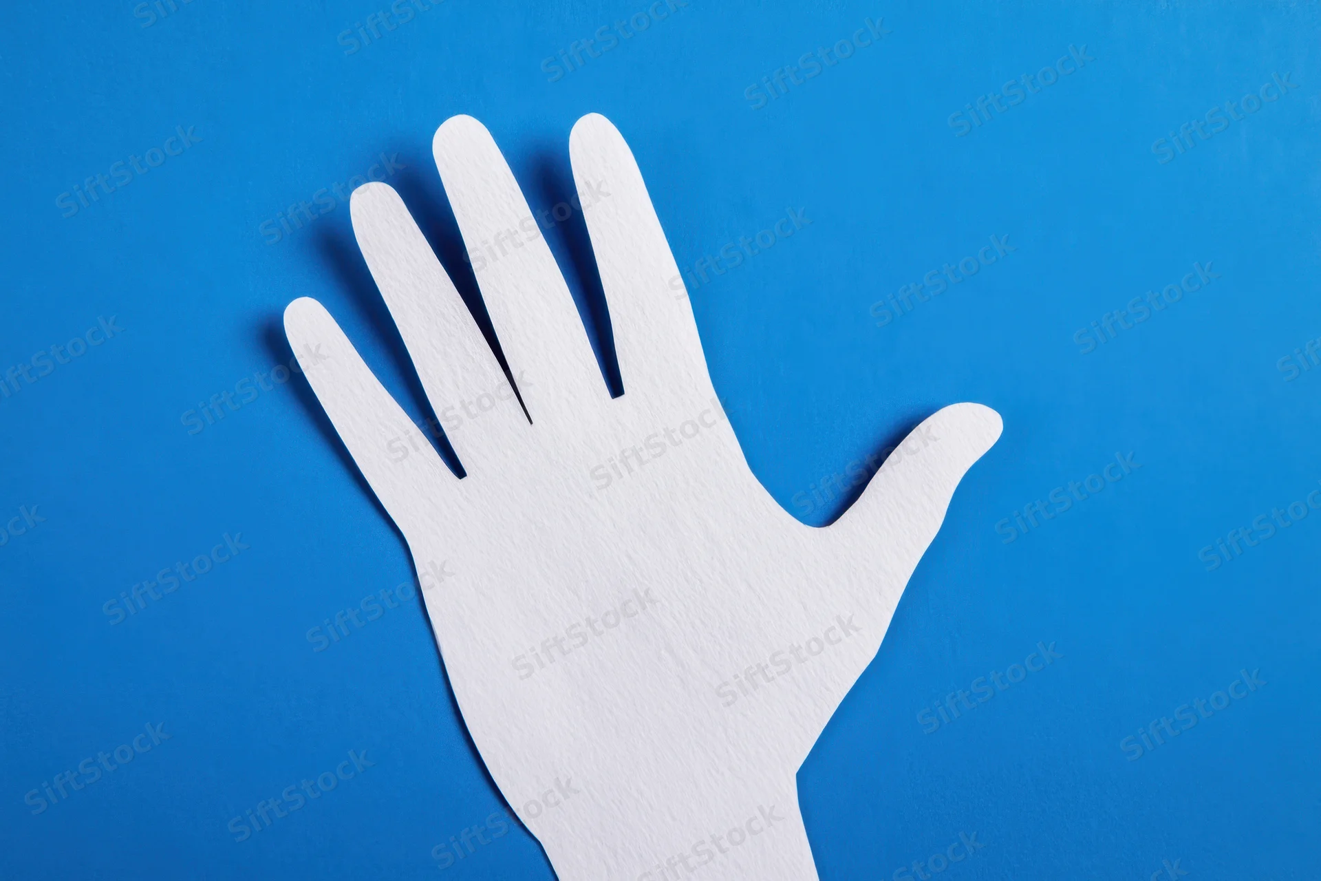 White paper hand cutout against vibrant blue background