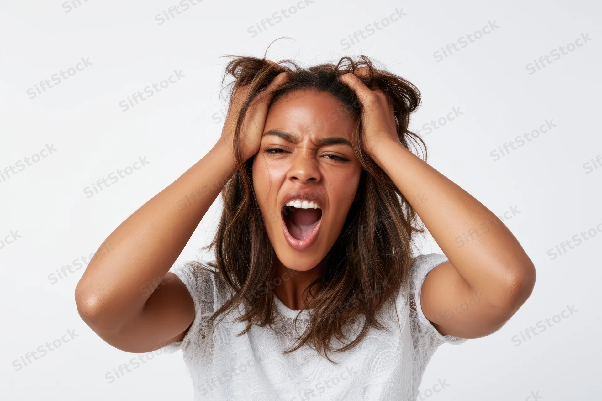 Young black woman screaming with hands in her hair against white background