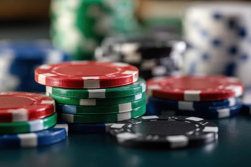 Stacks of colorful poker chips arranged on a green felt table with shallow depth of field and blurred background